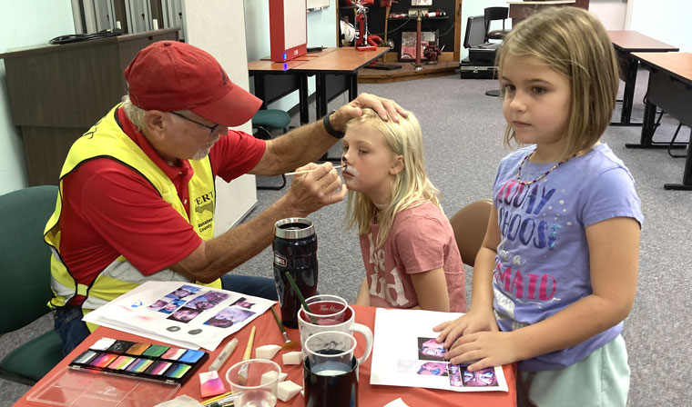 Dan Smith applies face paint to Open House visitor
